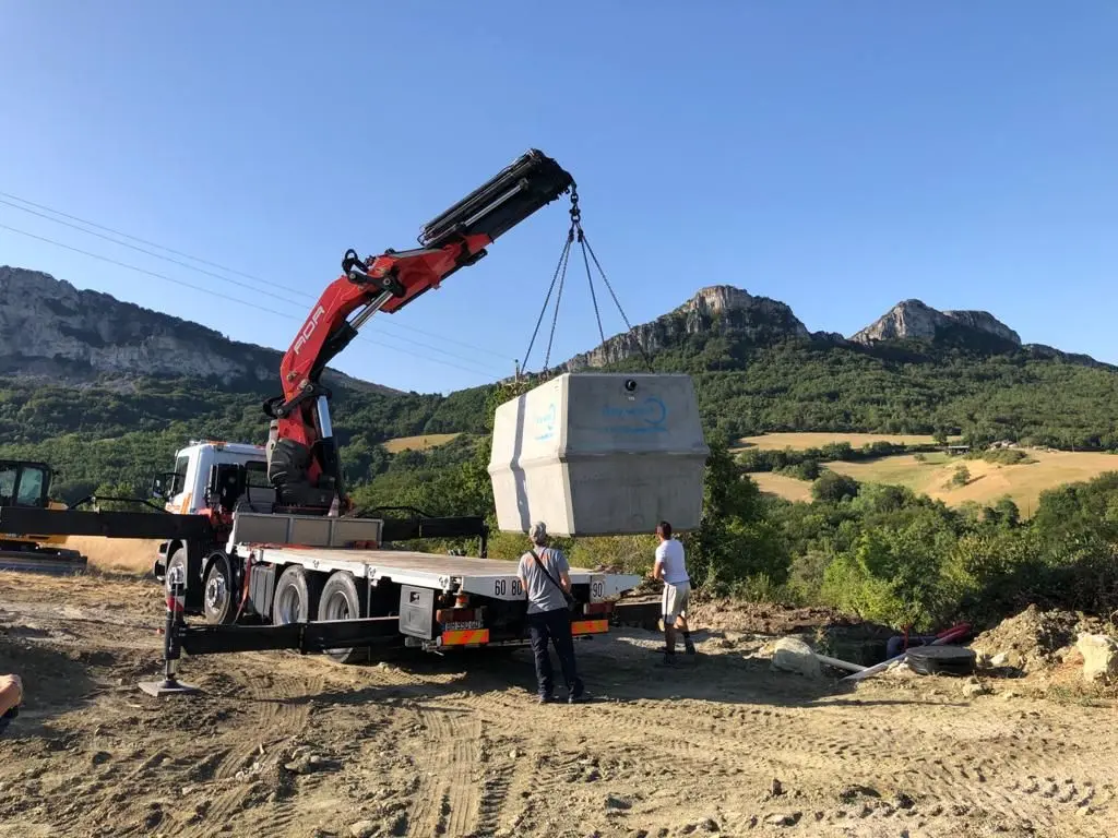 sur un chantier un camion soulève une cuve