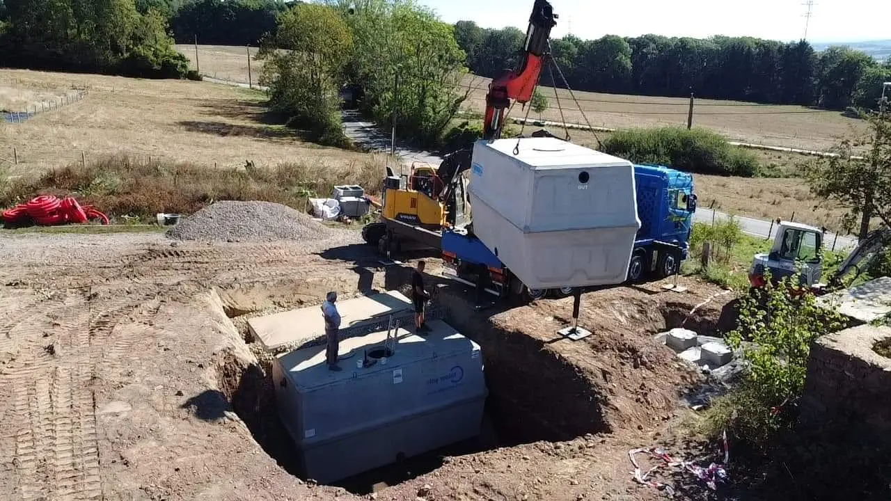 chantier avec une grue qui place une cuve d'eloy water dans le sol