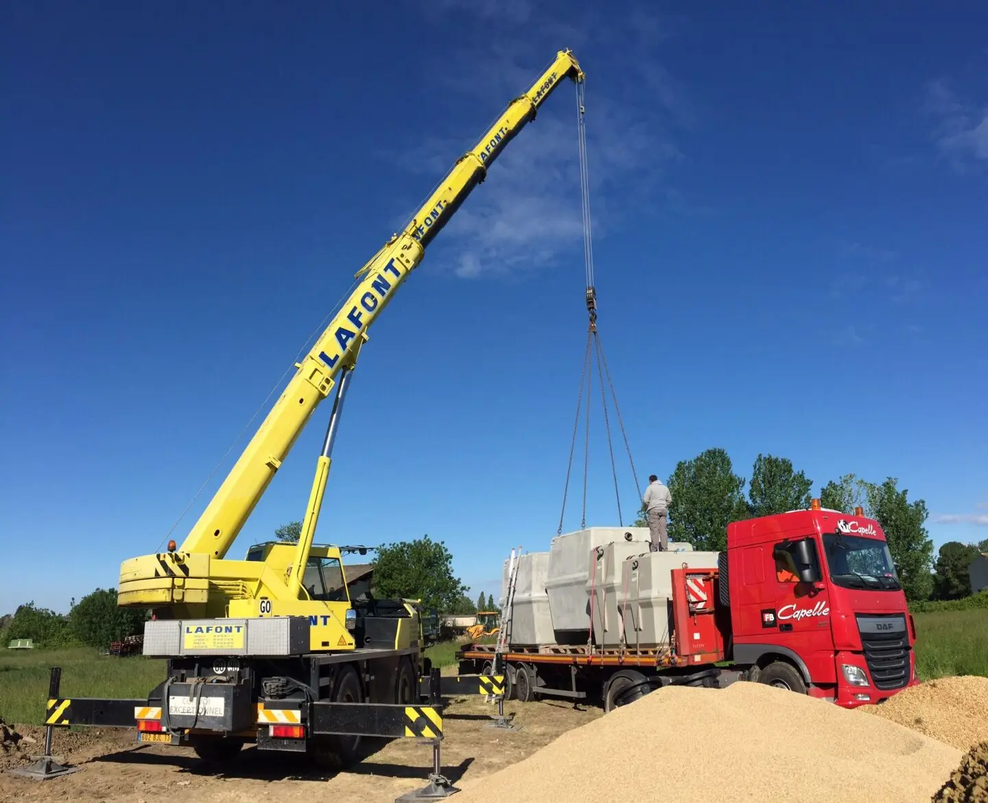 petite grue de chantier plaçant les microstations oxyfix sur un camion
