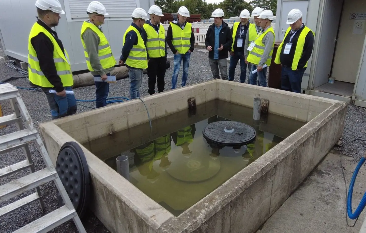 des personnes avec des casques et des gilets fluo sont autour de notre microstation oxyfix® lors d'une visite de l'usine d'eloy water