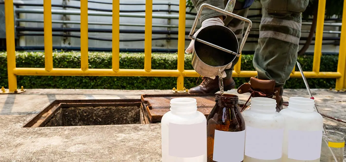 un ouvrier prend des échantillons d’eau usée dans une station d’épuration pour les faire analyser